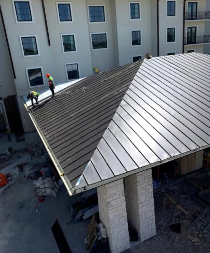 Crew installing standing seam metal roof panels on a commercial project in Grapevine